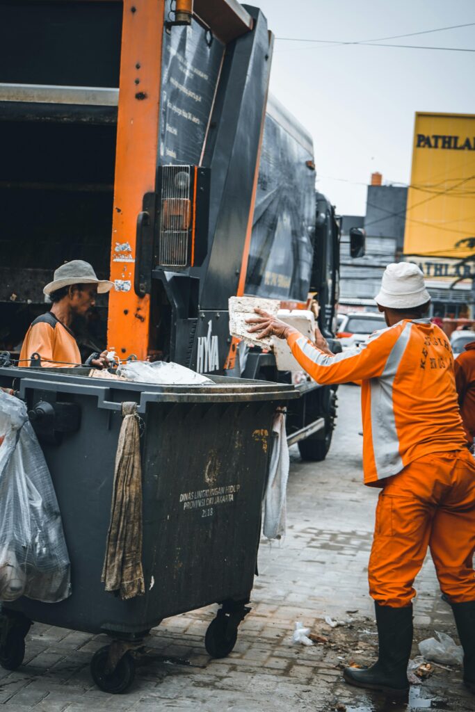 Sanitation workers disposing garbage into a truck on city street.